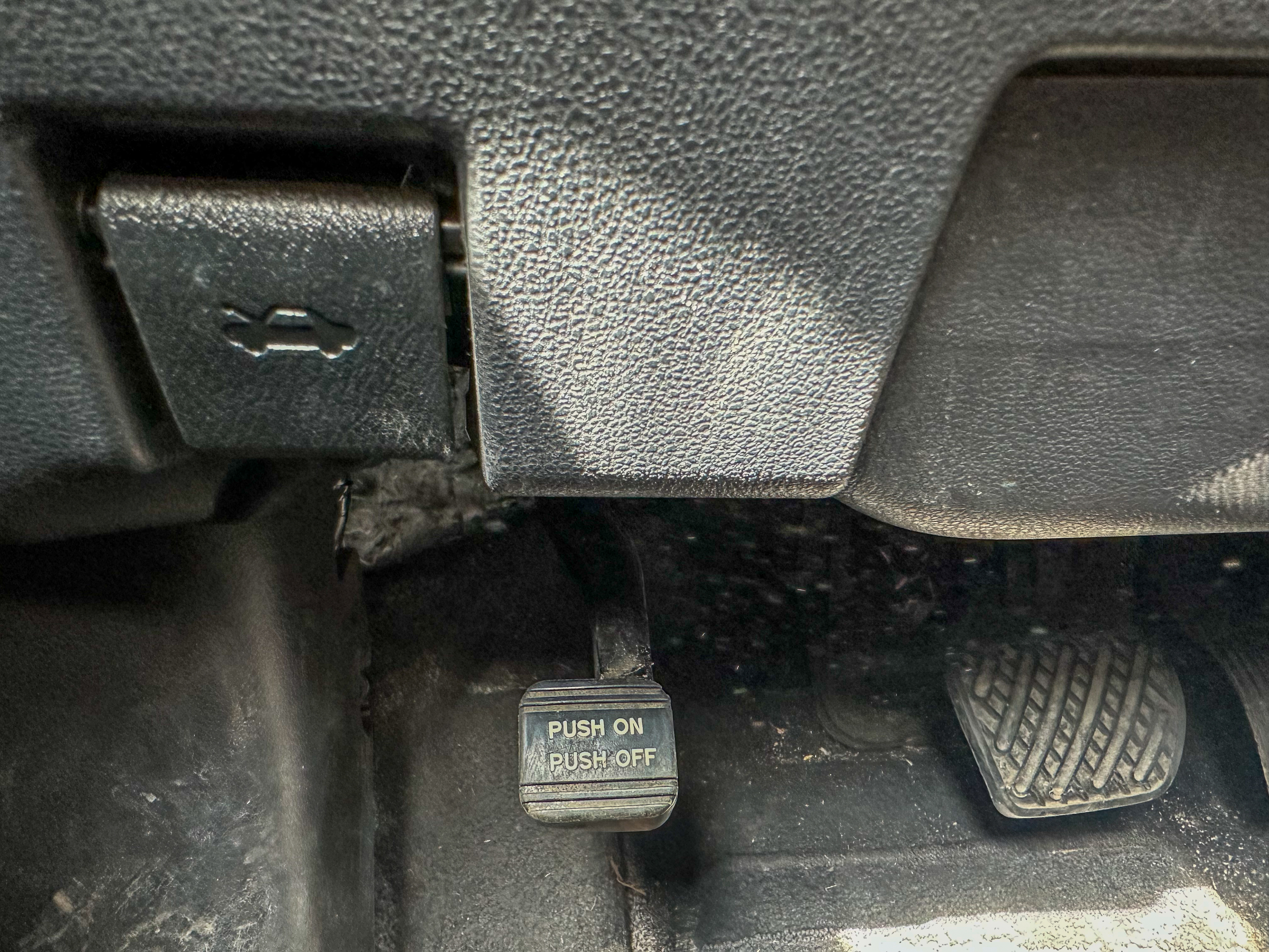 A photo of the Nissan Leaf parking brake lever in its off position, located near the gas and brake pedals